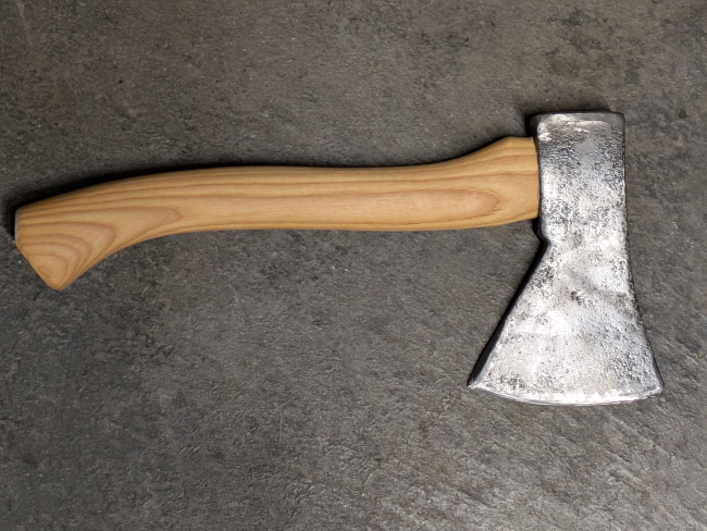 A restored hatchet/small axe lying on a concrete floor